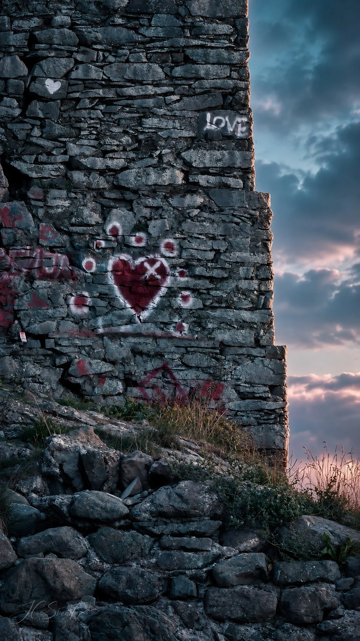 Love graffiti painted on a rough stone ruin under a brooding sky