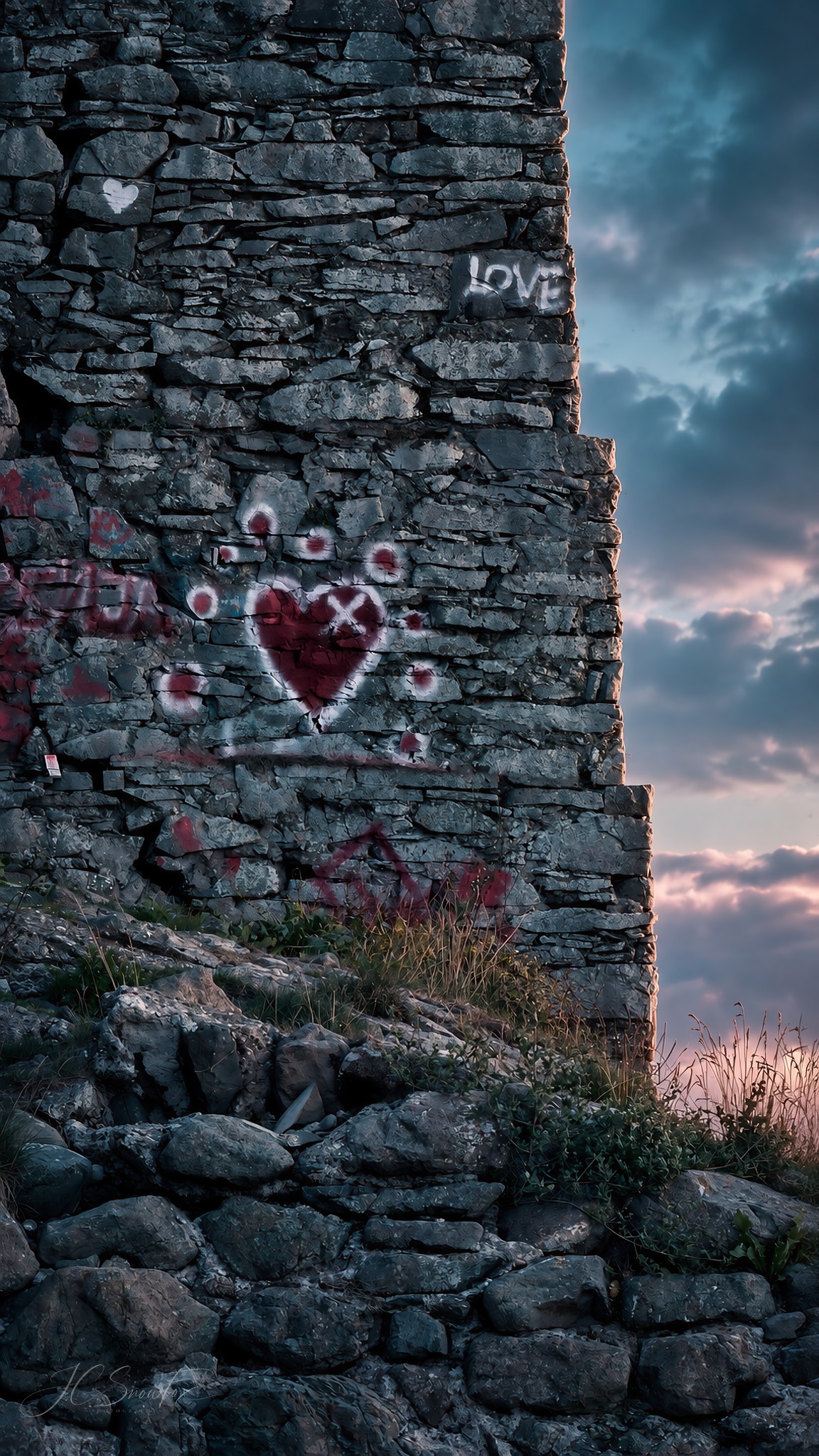 LOVE and a heart painted on a ruined stone wall beneath dramatic weather