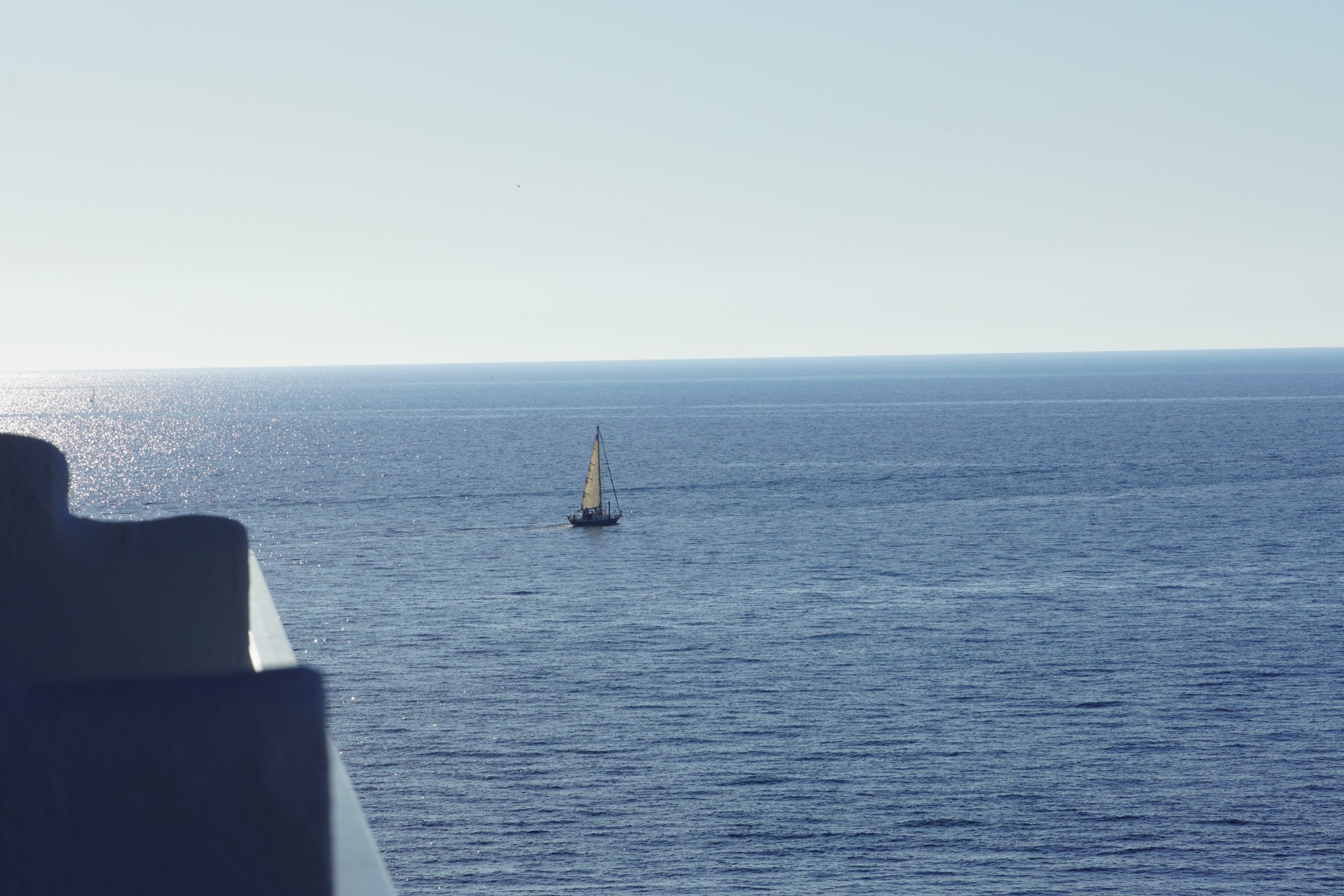 A solitary sailboat crossing bright blue Mediterranean water